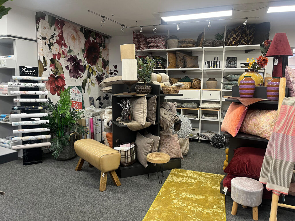 Dekoabteilung im Ewering-Fachmarkt mit Tapeten, Kissen, Teppichen, Lampen und Wohnaccessoires für Raumgestaltung