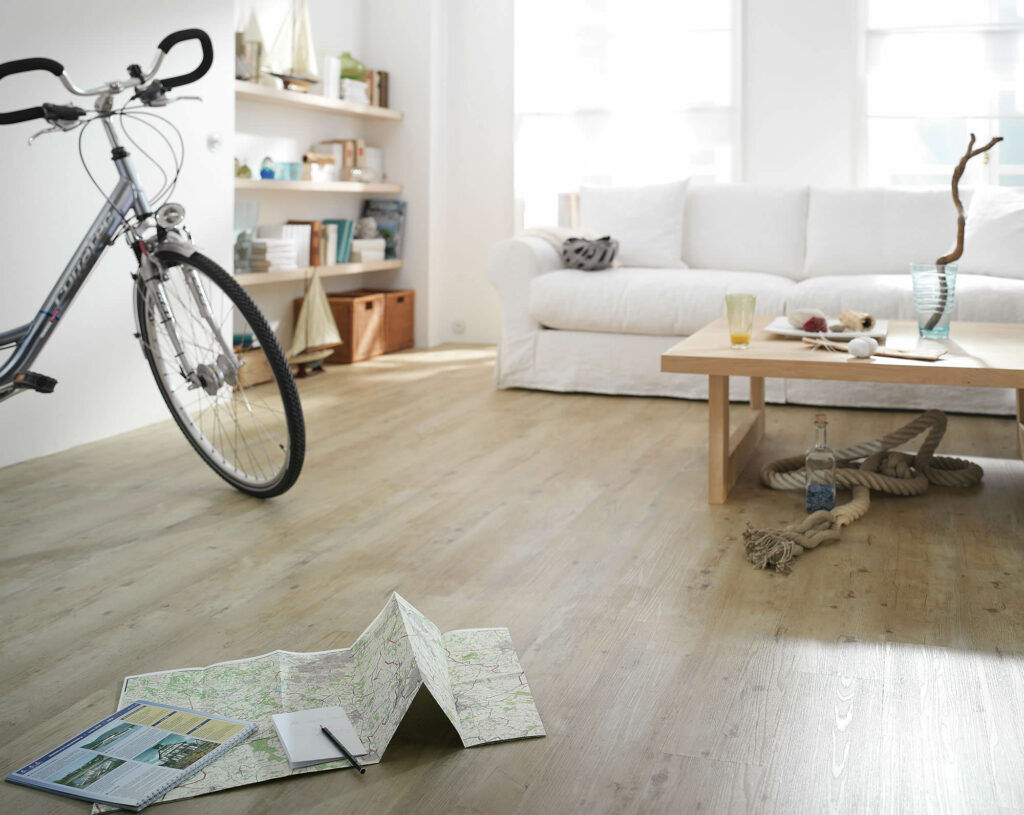 Heller Expona Domestic Designboden in Holzoptik in einem modernen Wohnbereich mit Sofa, Fahrrad und Wohnaccessoires.