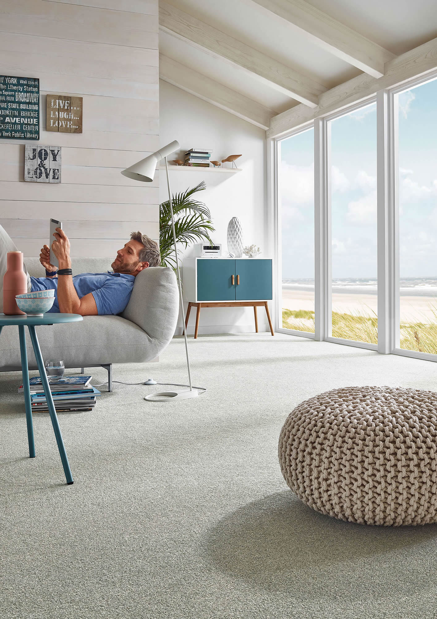 Modernes Wohnzimmer mit hell verlegtem Teppichboden und großzügiger Fensterfront. Das Bild zeigt sauber ausgeführte Bodenbelagsarbeiten mit weicher, heller und wohnlicher Raumwirkung.