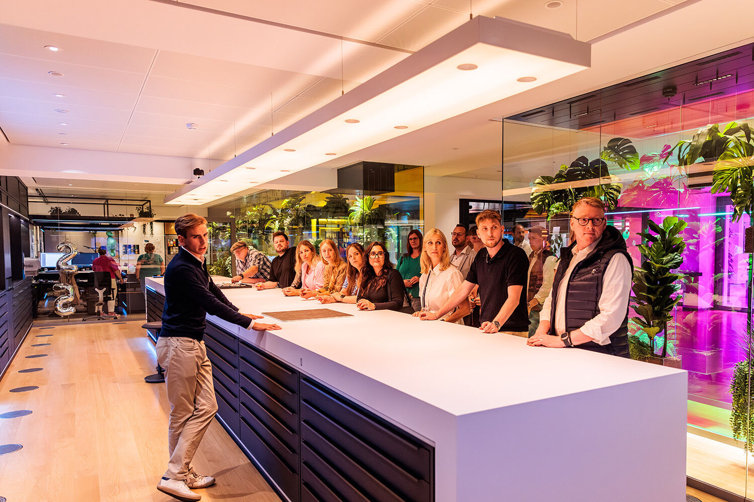 Gruppe von Mitarbeitenden und Gästen beim Ewering Sommerfest 2025 an einem langen Counter in einer modern beleuchteten Eventlocation