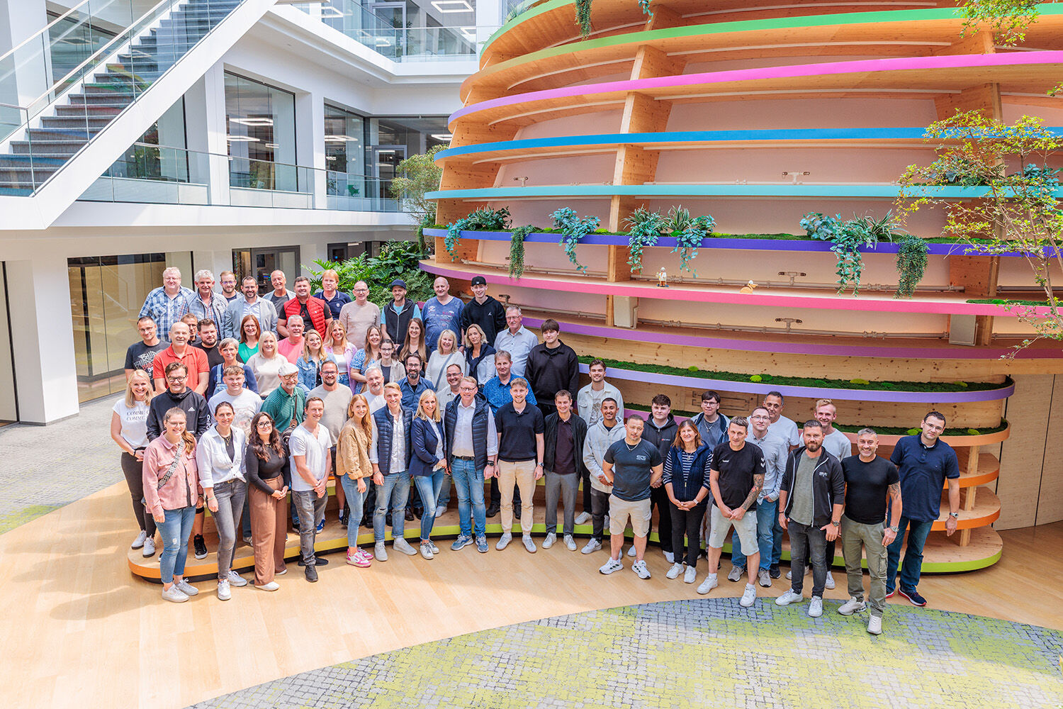 Gruppenfoto von Mitarbeitenden und Gästen beim Ewering Sommerfest 2025 in einer modernen Eventlocation mit farbig gestaltetem Innenbereich