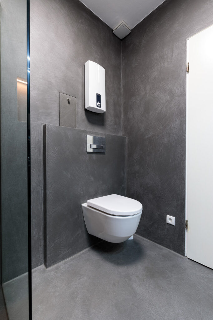 Modernes fugenloses Gäste-WC mit dunkelgrauen Wand- und Bodenflächen sowie wandhängender Toilette.