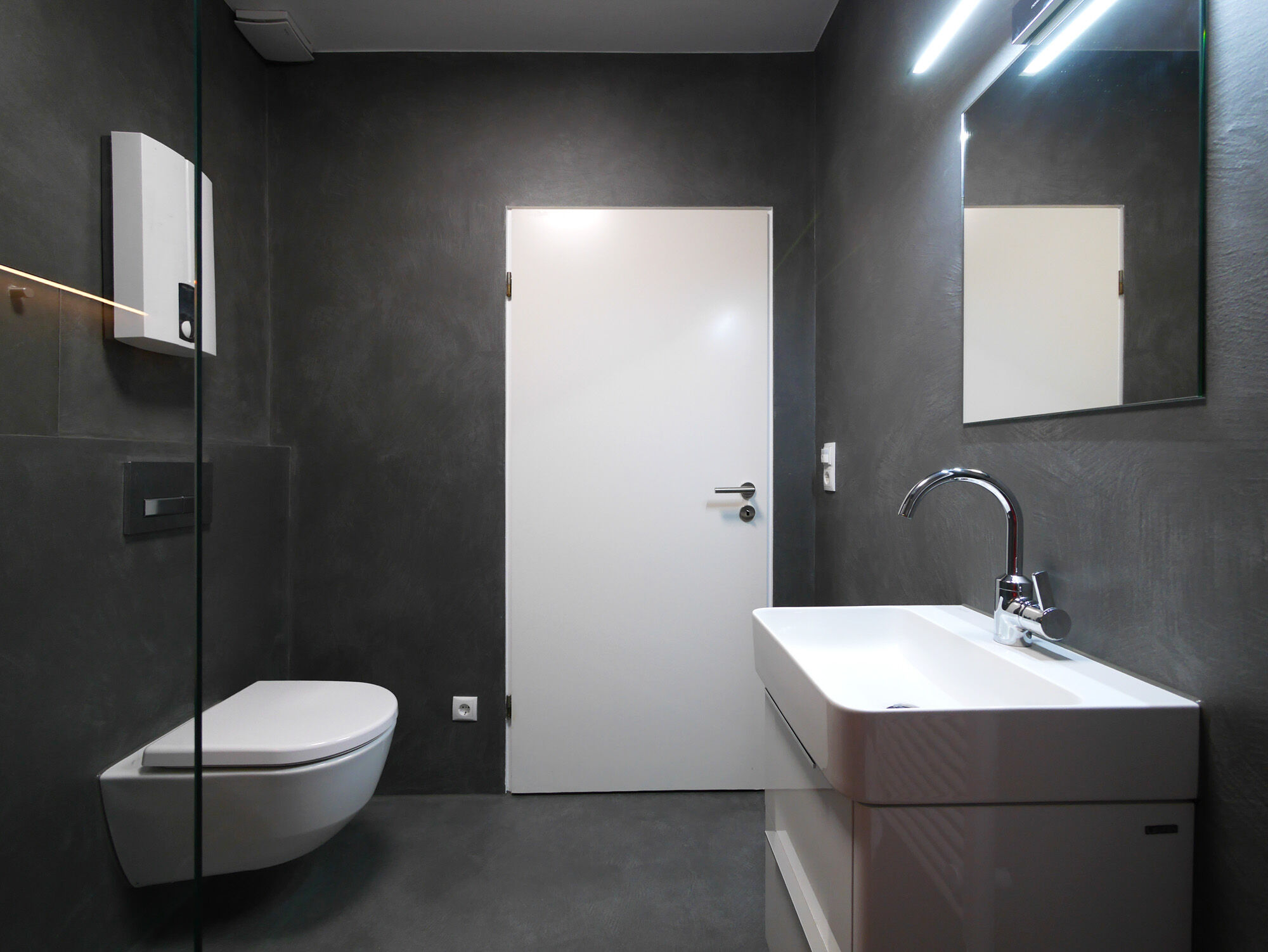 Dunkles Badezimmer mit Großflächenspiegeln, floating Waschtisch und wandhängendem WC – Exklusives Frescolori-Badezimmer