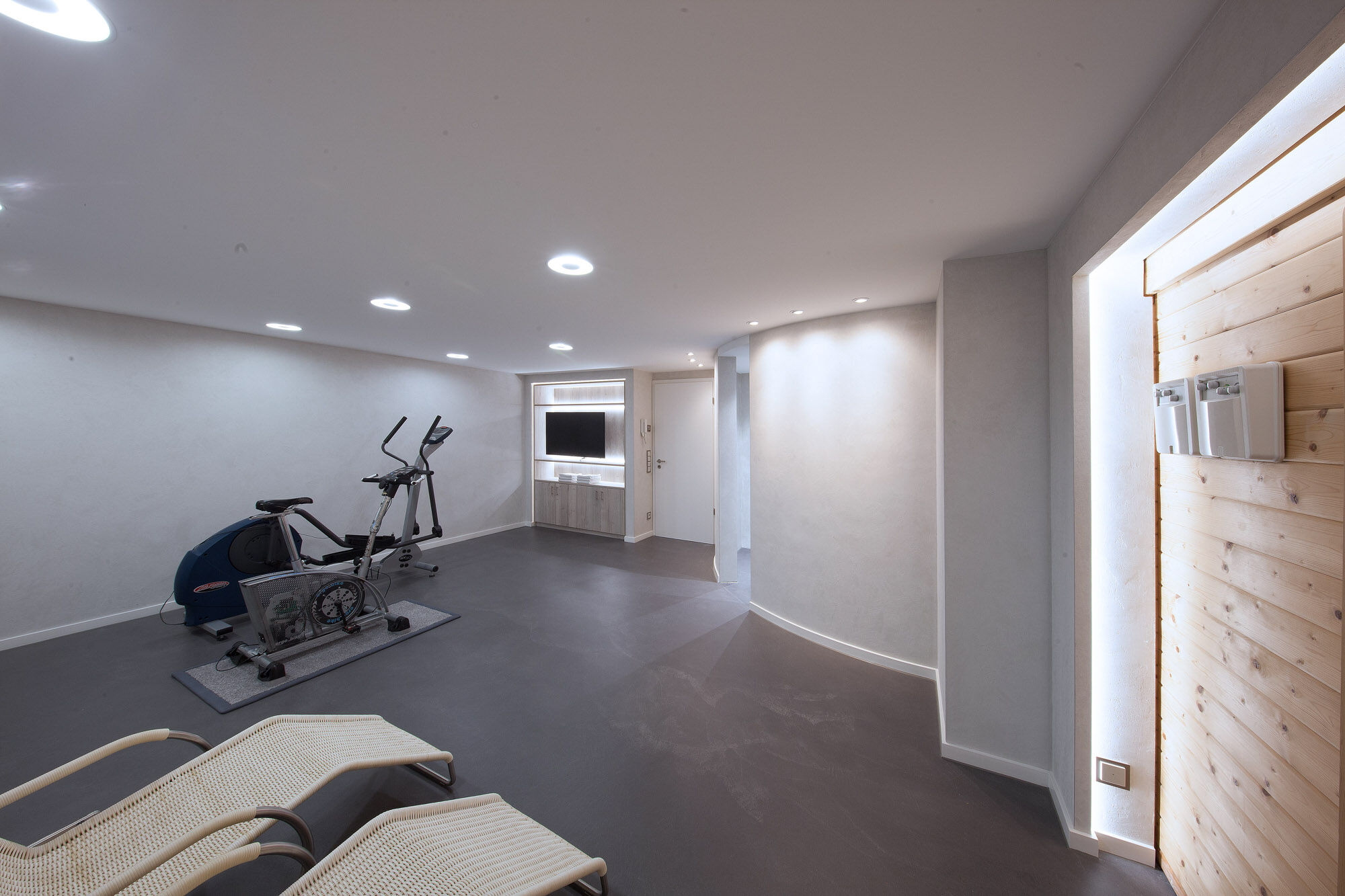 Fitness- und Wellnessraum mit Heimtrainer und TV-Wand – Exklusives Frescolori-Badezimmer