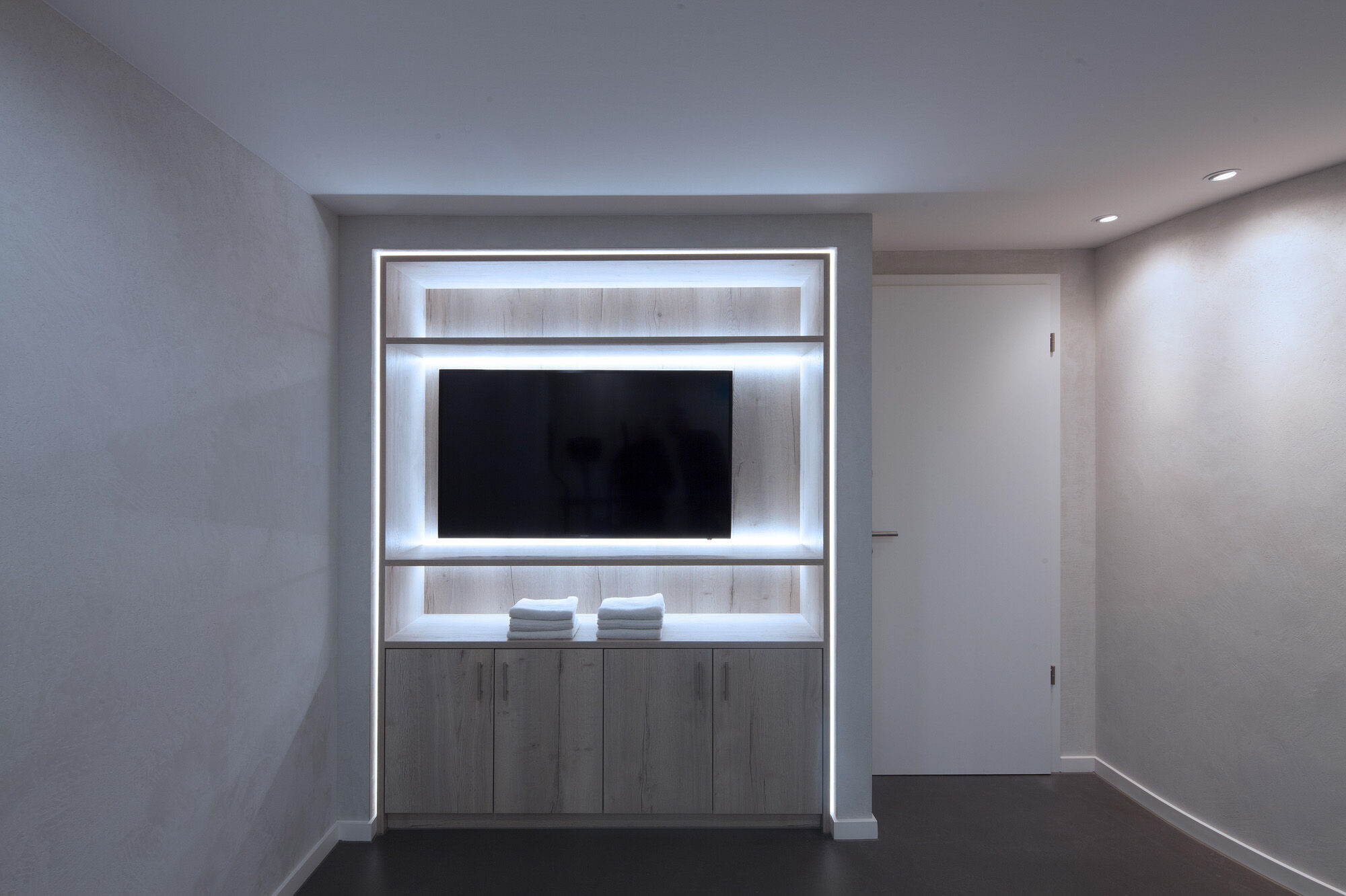 Wellness-Wohnbereich mit TV-Nische, LED-Regal und Holzbettbereich – Exklusives Frescolori-Badezimmer