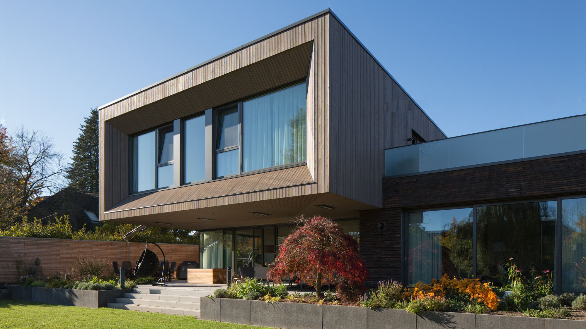Gartenansicht mit moderner Holzfassade des Wohnhauses, Exklusives Wohnhaus Münsterland