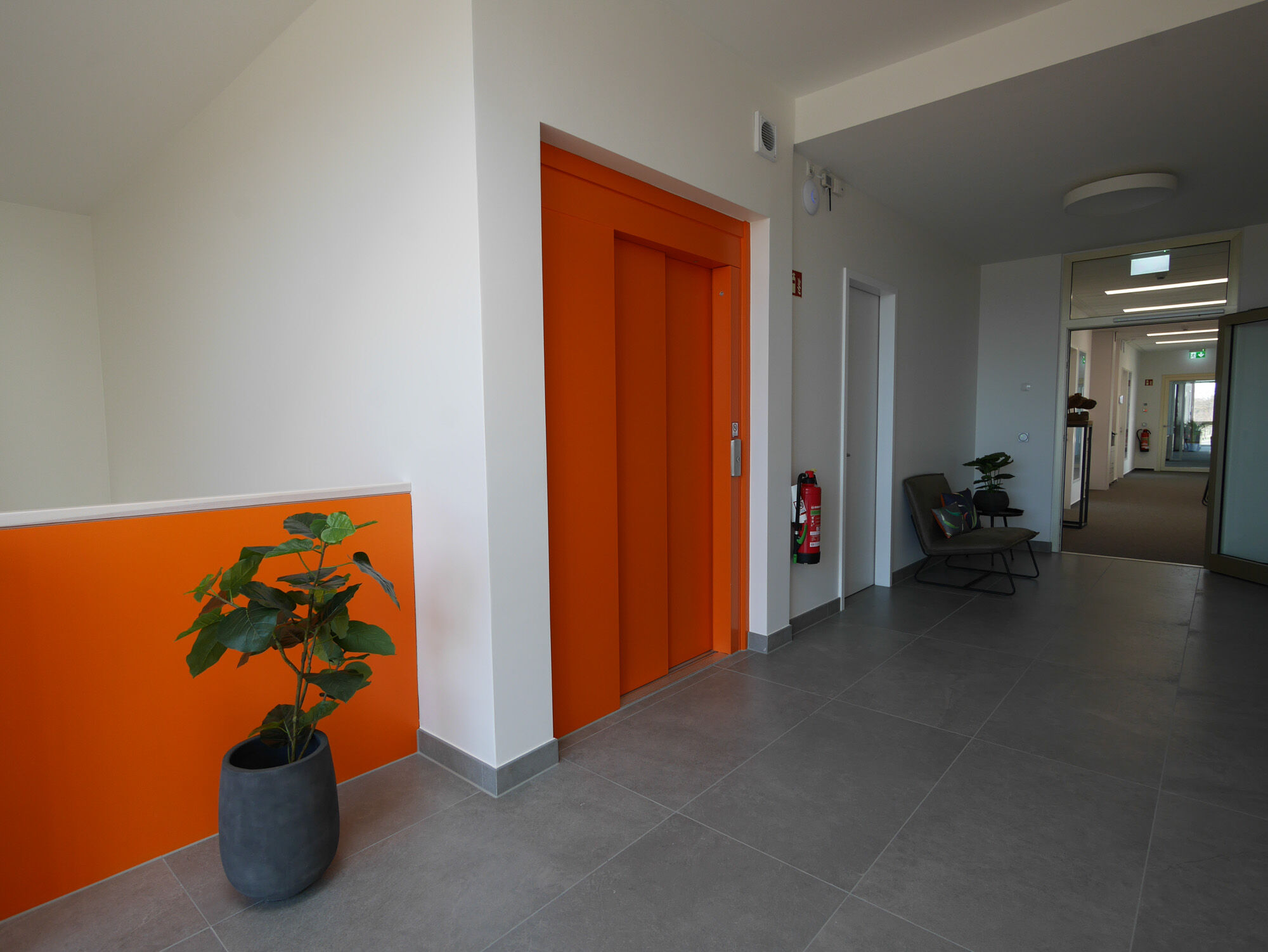 Flur mit orange Aufzugroboter und Akzentwand in Gebäude B – IDPM Gebäude B