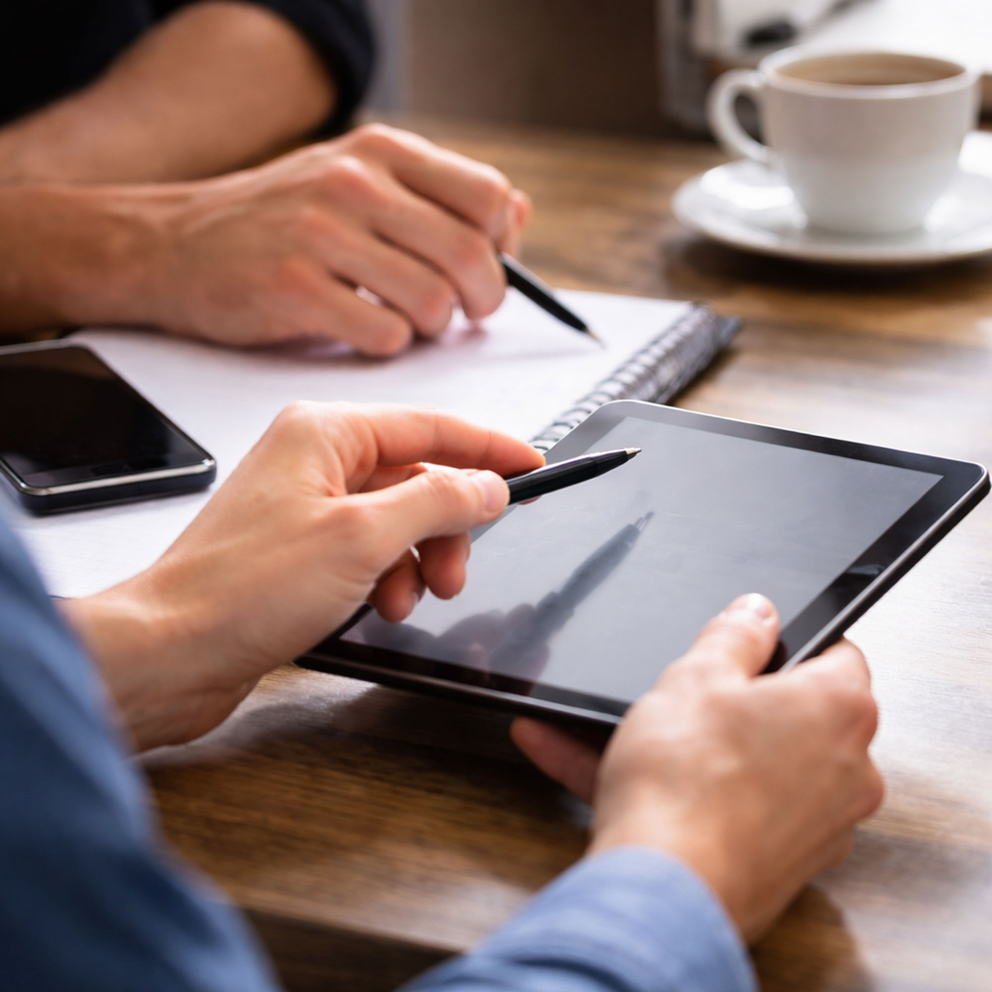 Beratungsgespräch mit Tablet, Notizblock und Kaffeetasse zur Bedarfsanalyse - Stromaggregat mieten