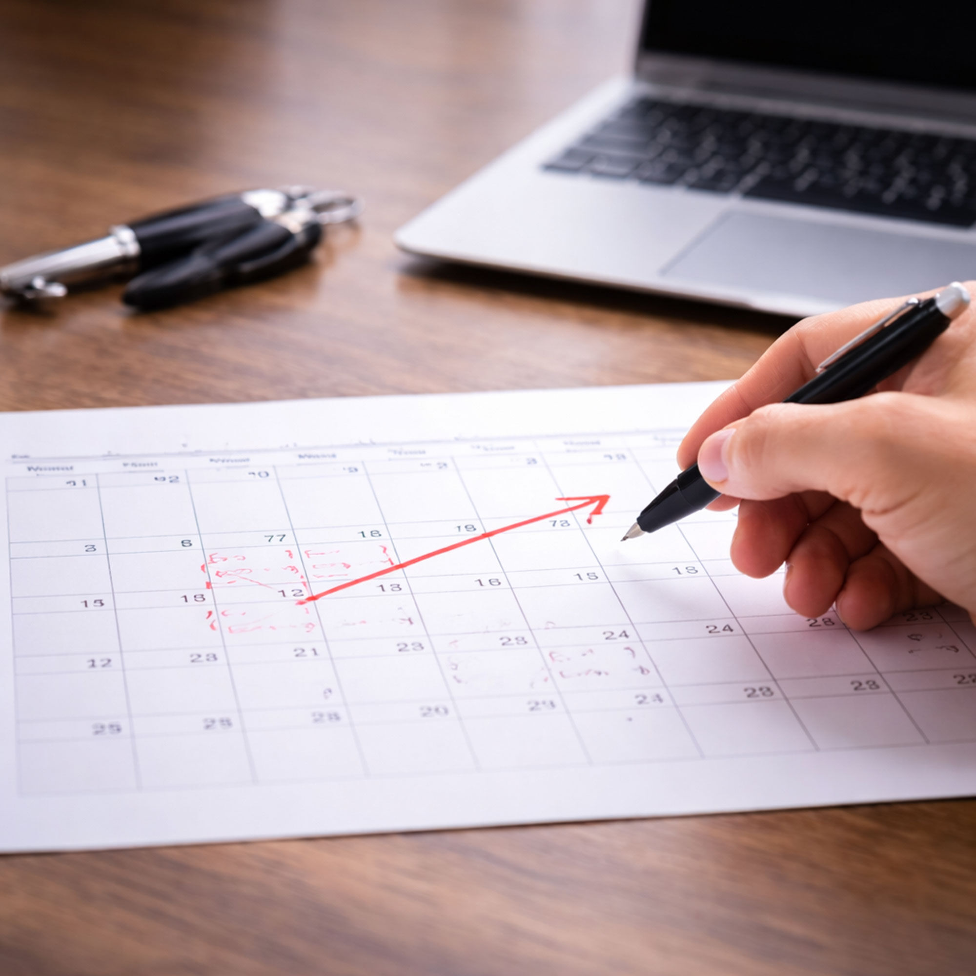 Hand markiert Mietzeitraum mit rotem Stift auf einem gedruckten Kalender - Stromaggregat mieten