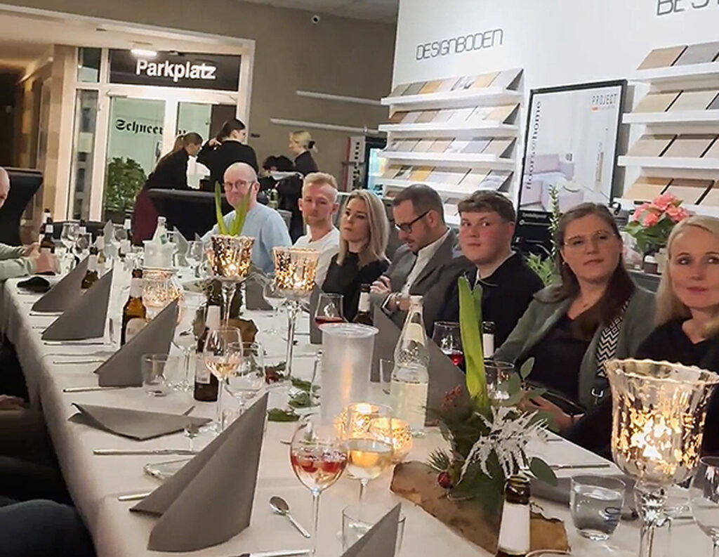 Ewering-Mitarbeiter sitzen bei einer Weihnachtsfeier in Reken an einer festlich gedeckten Tafel im Fachmarkt
