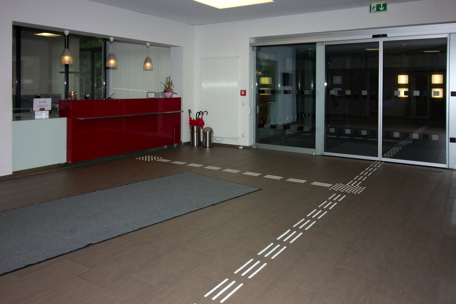 Blindenleitsystem mit taktilen Leitstreifen im Empfangsbereich vor Rezeption und Schiebetür.