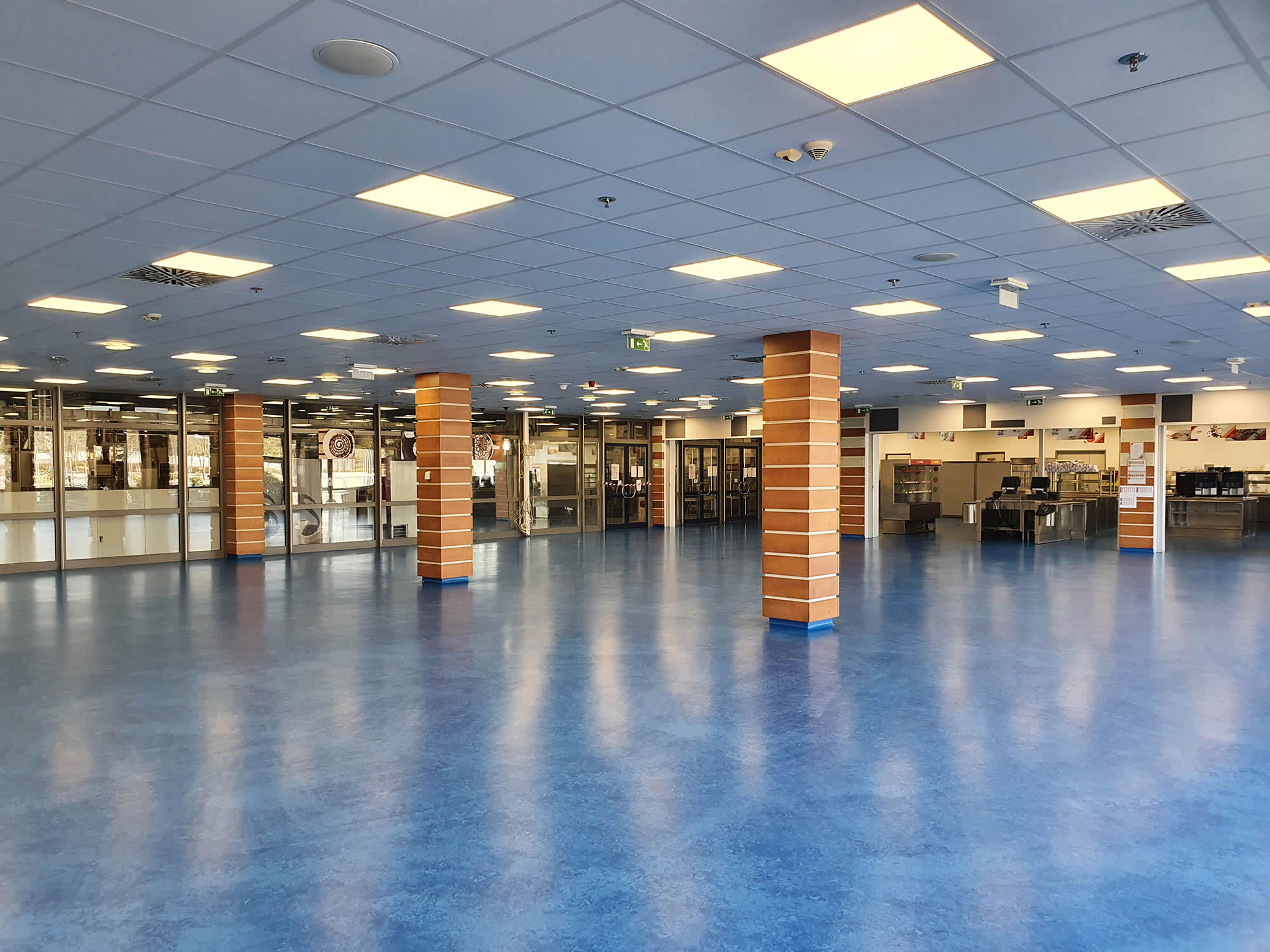 Großzügige Kantine mit frisch versiegeltem blauem Boden in spiegelglänzender Optik - Bodenbelagsarbeiten