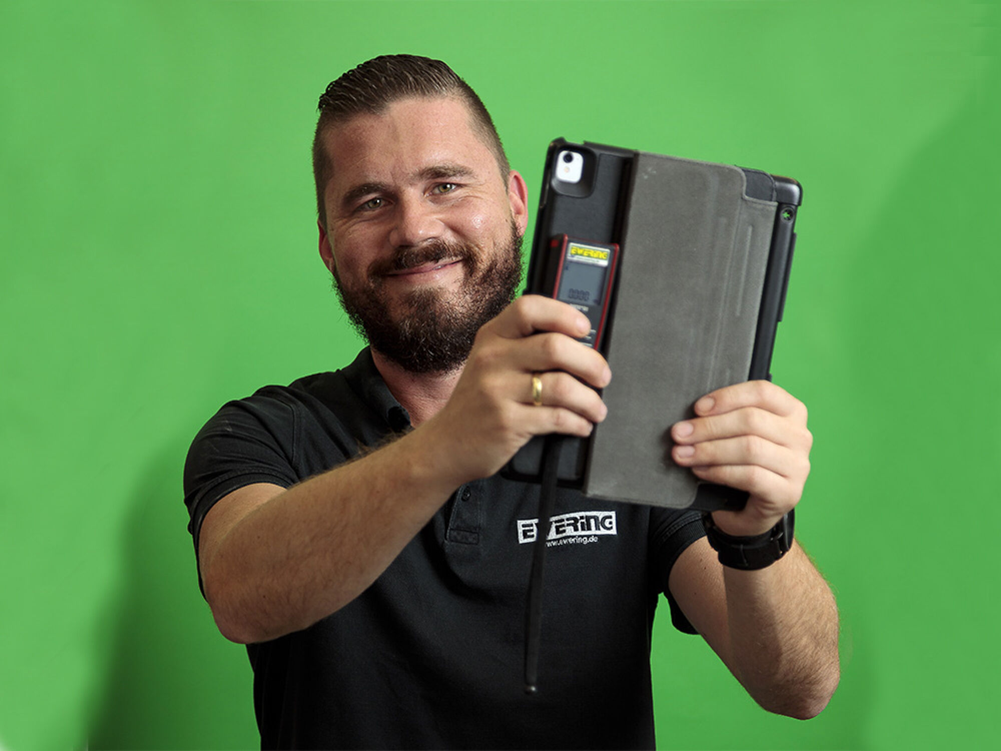 Ewering Mitarbeiter mit Tablet und digitalem Messgerät vor grünem Hintergrund