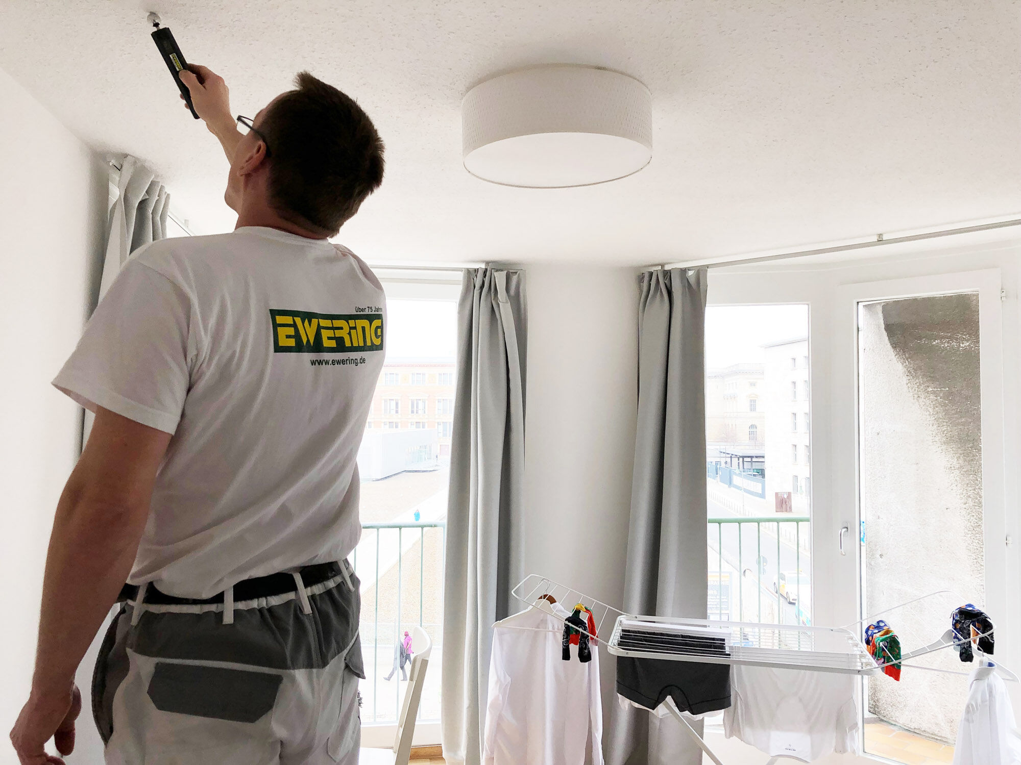 Mitarbeiter misst Deckenfeuchte mit Hydromette in heller Wohnung - Schimmelsanierung