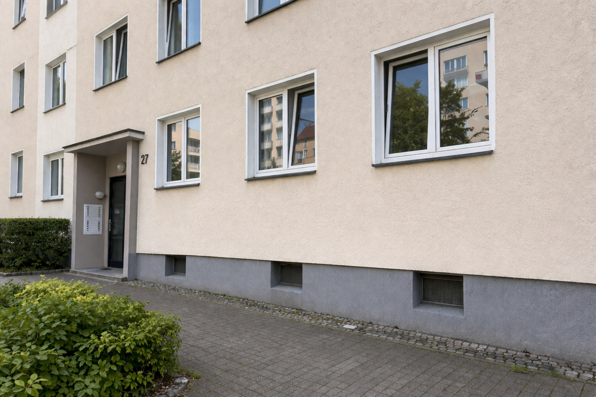 Mehrfamilienhaus mit cremefarbener Fassade ohne Graffiti nach Reinigung - Graffitientfernung