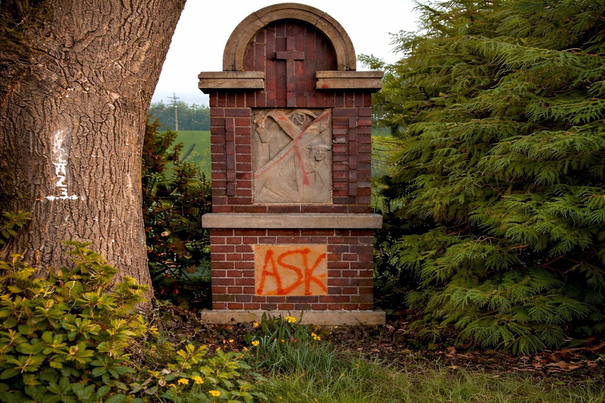 Religiöser Klinker-Bildstock mit orangem ASK-Tag vor der Reinigung - Graffitientfernung