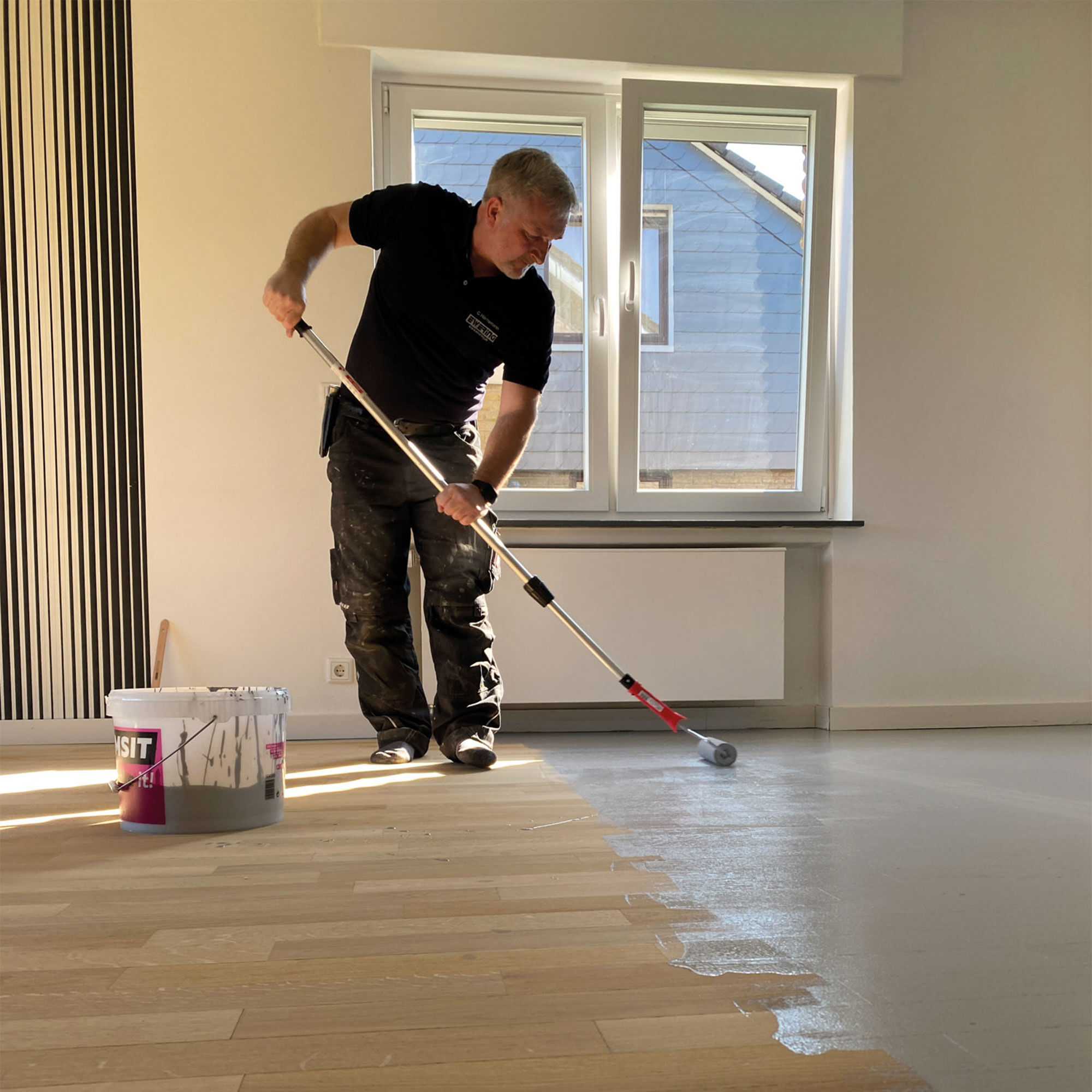 Mitarbeiter behandelt Parkett im vierten Schritt mit Versiegelung im Wohnraum - Parkett abschleifen