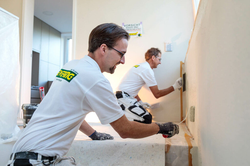 Zwei Ewering Mitarbeiter streichen Wände in einem Treppenhaus.